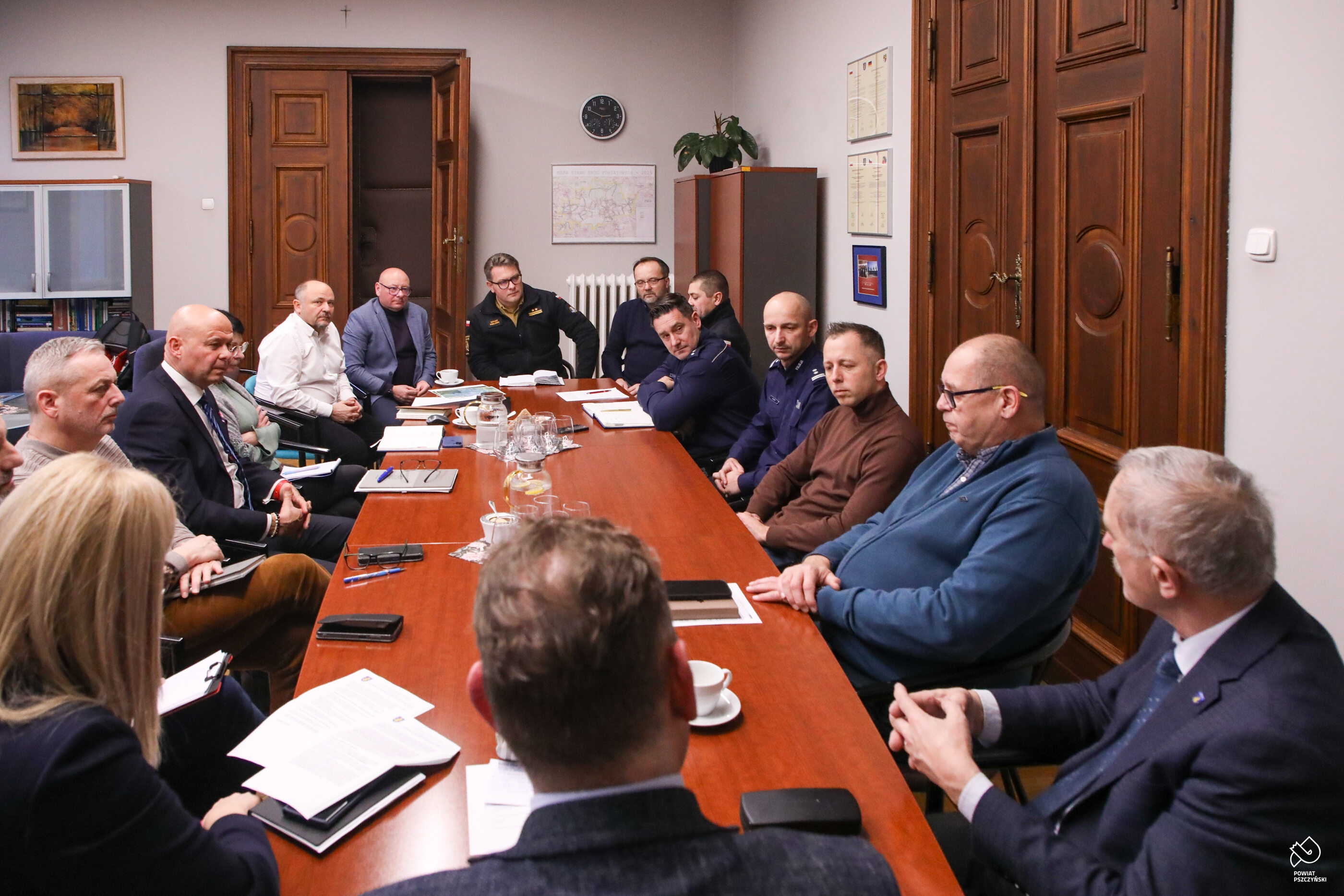 Grupa osób siedząca przy stole podczas spotkania Powiatowego Zespołu Zarządzania Kryzysowego